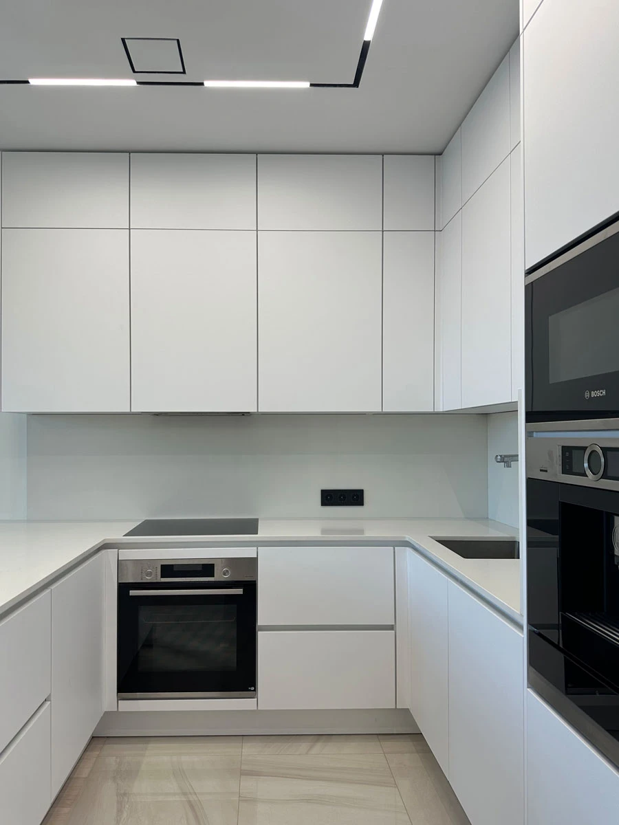 Белая п-образня немецкая кухня. Фасады без ручек и отпечатков пальцев